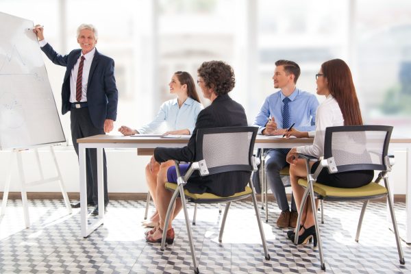 Smiling senior businessman conducting presentation Smiling senior businessman conducting presentation in front of coworkers. Aged financial manager explaining new strategy to colleagues.
Business presentation concept